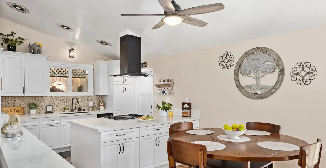 Kitchen with white raised panel cabinets and wood dining table.