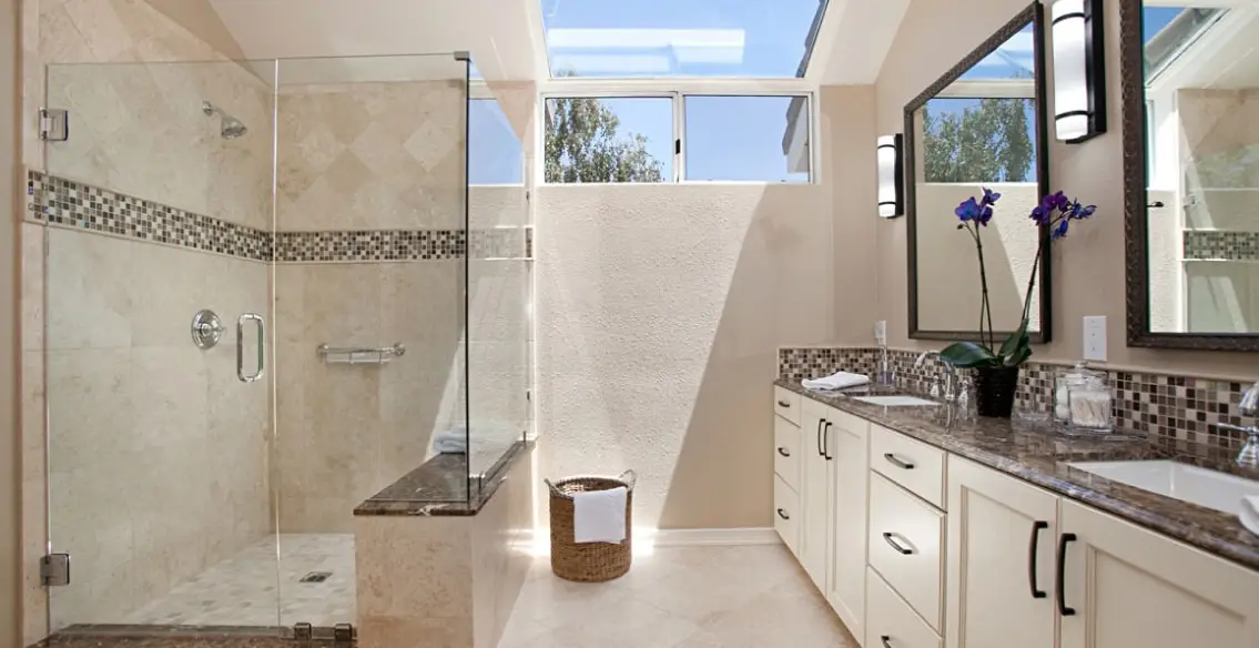 Master bathroom with custom tiled shower with a built in bench seat. Double sink vanity with cream colored cabinets, brown granite top, and chrome fixtures.