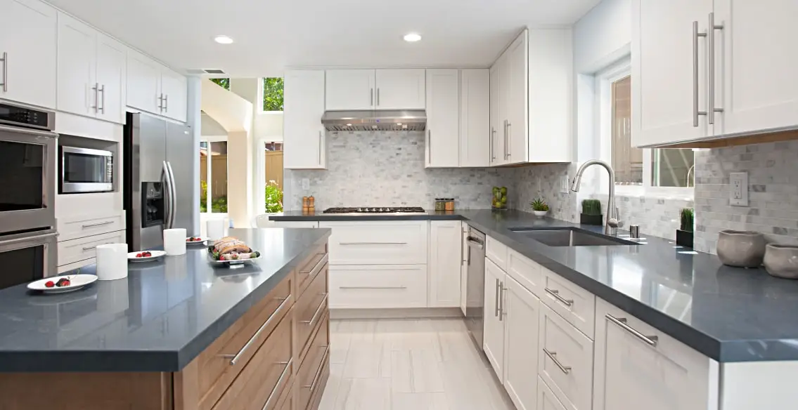 Two tone kitchen with white painted cabinets on perimeter and maple wood stained on Island. Charcoal Soapstone quartz countertops.