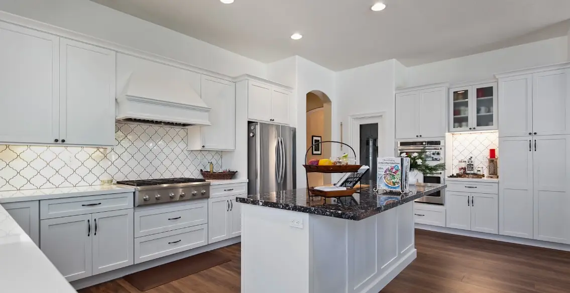 U shaped kitchen with and island. White painted shaker cabinets, custom wood hoot, and quartz tops.