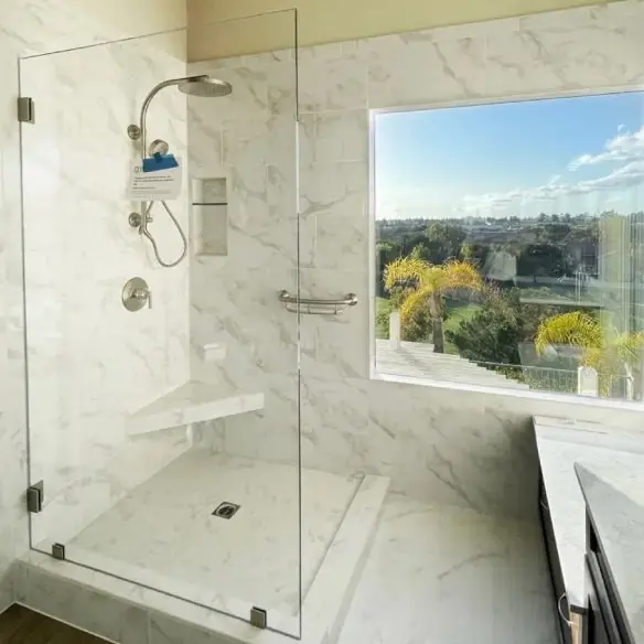 Master bath tiled in shower with rain shower head and removable hand shower. Glass panel on left.