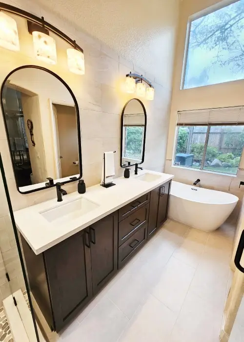 Bathroom with a free standing tub and a double sink vanity with dark wood cabinets and black fixtures