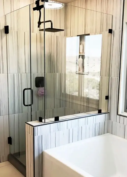 Shower in master bathroom with tile walls, black fixtures, and frameless glass shower door