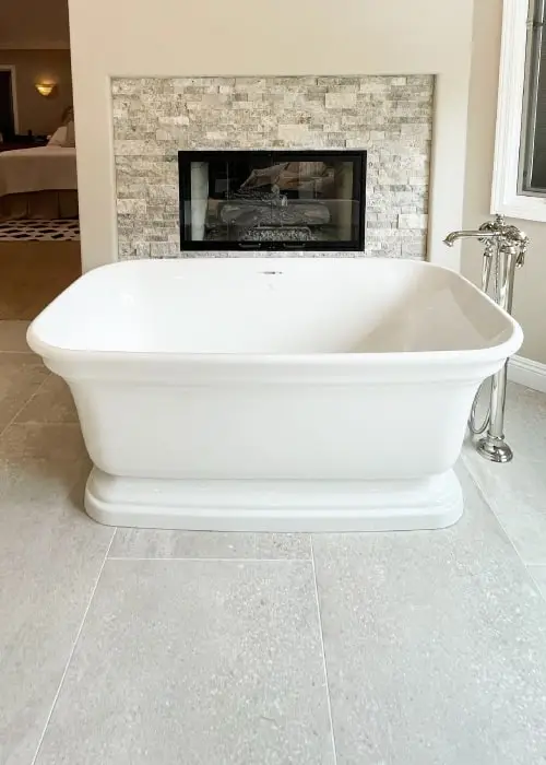 Free standing tub in front of a fireplace with a floor mounted tub filler